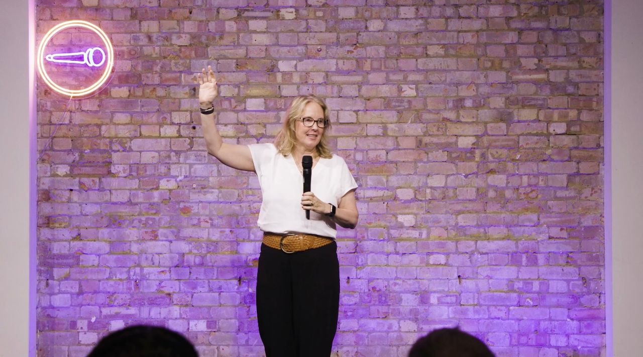 Cara Cunniff speaking on stage with her hand raised